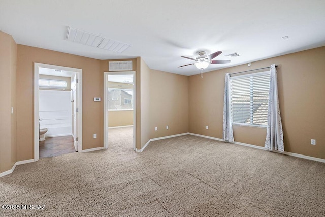 carpeted spare room with visible vents, baseboards, and ceiling fan