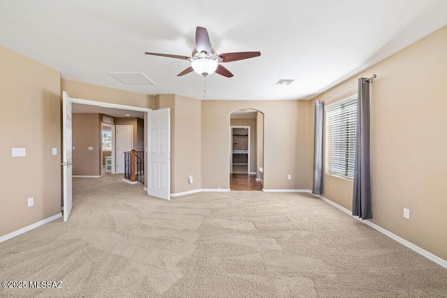 interior space featuring visible vents, ceiling fan, baseboards, carpet floors, and arched walkways