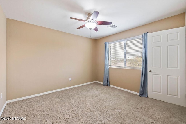 carpeted empty room with visible vents, baseboards, and ceiling fan