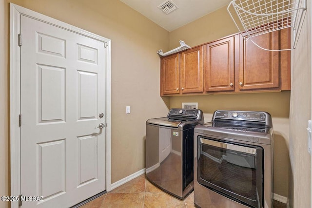 laundry room featuring light tile patterned floors, baseboards, visible vents, washing machine and clothes dryer, and cabinet space