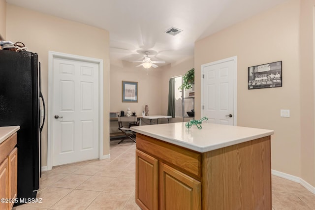 kitchen with light tile patterned floors, visible vents, a kitchen island, and freestanding refrigerator