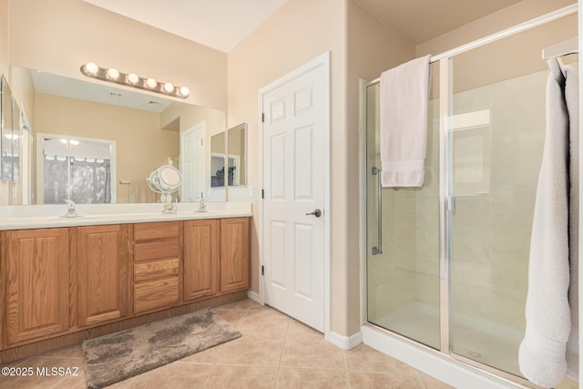 bathroom with tile patterned flooring, a shower stall, double vanity, and a sink