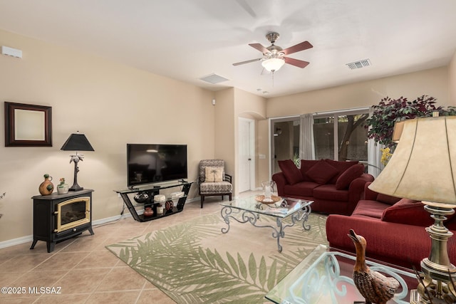 living area featuring visible vents, ceiling fan, a wood stove, and tile patterned flooring