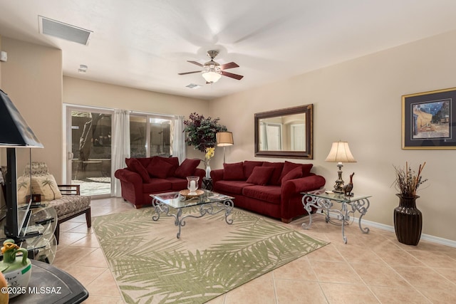 living area featuring light tile patterned floors, visible vents, a ceiling fan, and baseboards