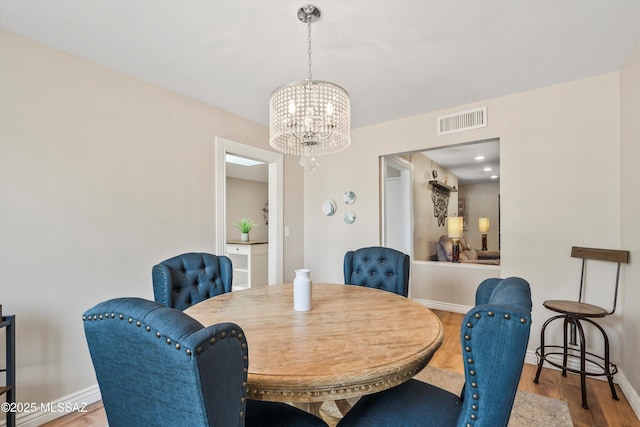 dining space featuring a chandelier, visible vents, baseboards, and wood finished floors