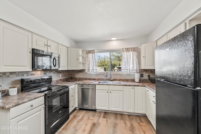 kitchen featuring decorative backsplash, white cabinetry, black appliances, and a sink