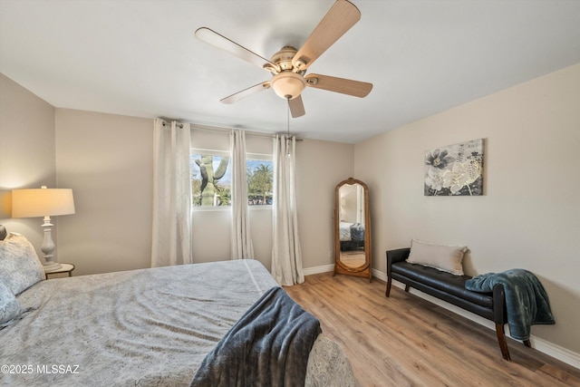 bedroom with a ceiling fan, baseboards, and light wood-type flooring