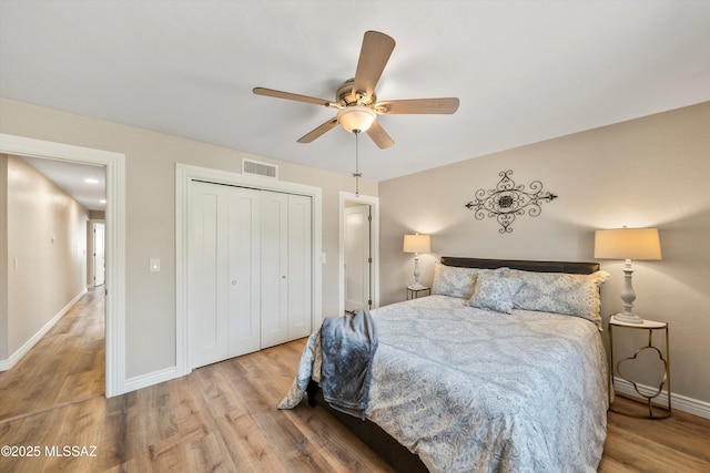 bedroom featuring visible vents, baseboards, a closet, and wood finished floors