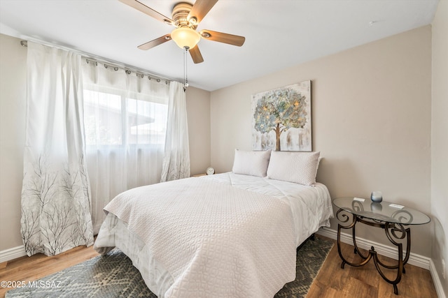 bedroom with a ceiling fan, wood finished floors, and baseboards