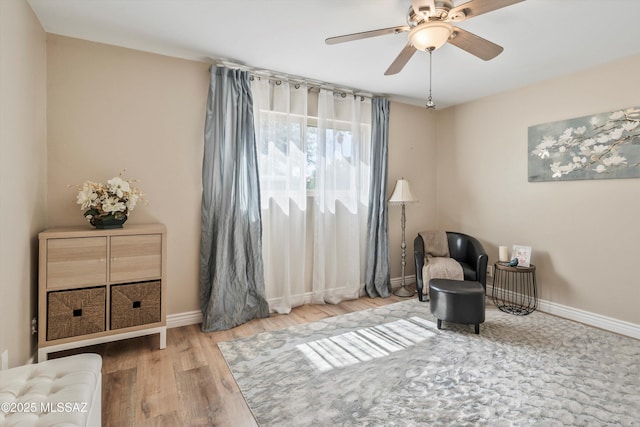 sitting room featuring a ceiling fan, wood finished floors, and baseboards