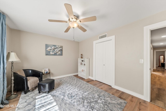 sitting room featuring visible vents, ceiling fan, baseboards, and wood finished floors