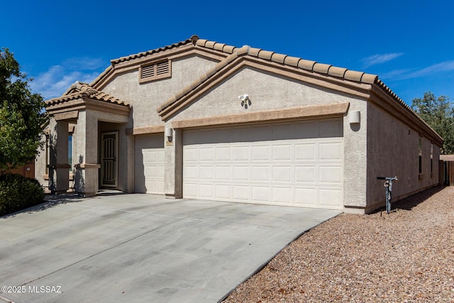 view of front of property featuring concrete driveway, a tiled roof, an attached garage, and stucco siding