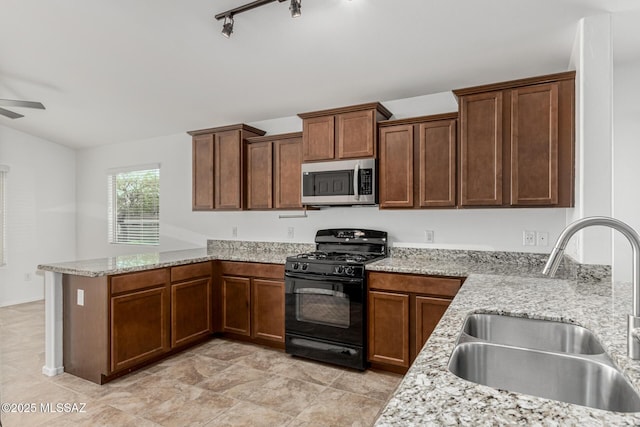 kitchen with a peninsula, ceiling fan, a sink, black gas range, and stainless steel microwave