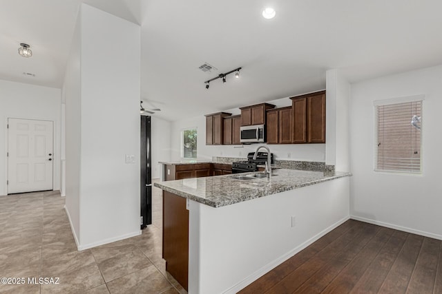 kitchen with light stone countertops, visible vents, a peninsula, a sink, and black appliances