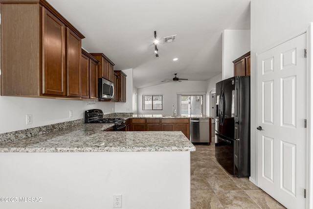 kitchen featuring visible vents, a peninsula, lofted ceiling, a sink, and black appliances