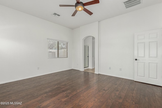 spare room with visible vents, arched walkways, a ceiling fan, and dark wood-style flooring