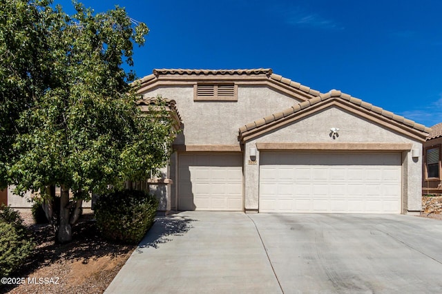 view of front facade featuring a tile roof, stucco siding, concrete driveway, and a garage