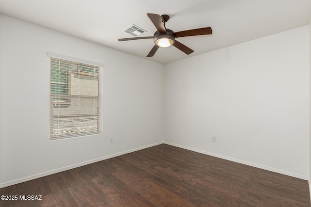 unfurnished room with dark wood finished floors, visible vents, a ceiling fan, and baseboards