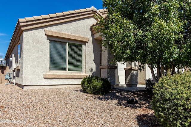 view of property exterior with a tile roof and stucco siding