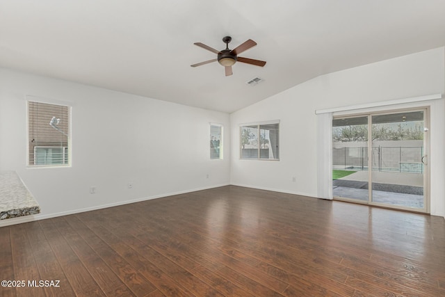 empty room with visible vents, lofted ceiling, dark wood-type flooring, and baseboards