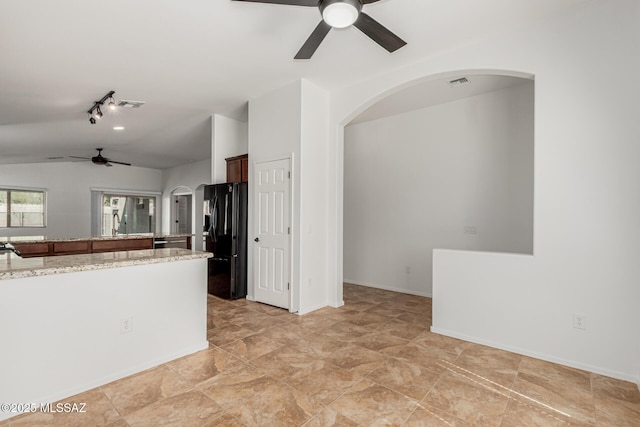 kitchen with visible vents, arched walkways, vaulted ceiling, and freestanding refrigerator