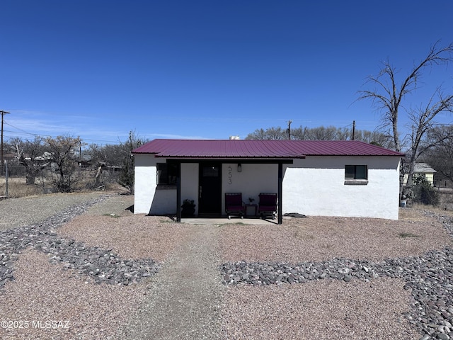 rear view of house with stucco siding and metal roof