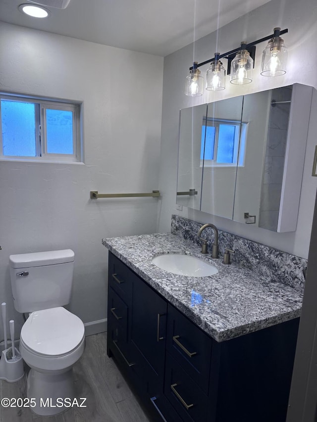 bathroom featuring vanity, toilet, baseboards, and a wealth of natural light