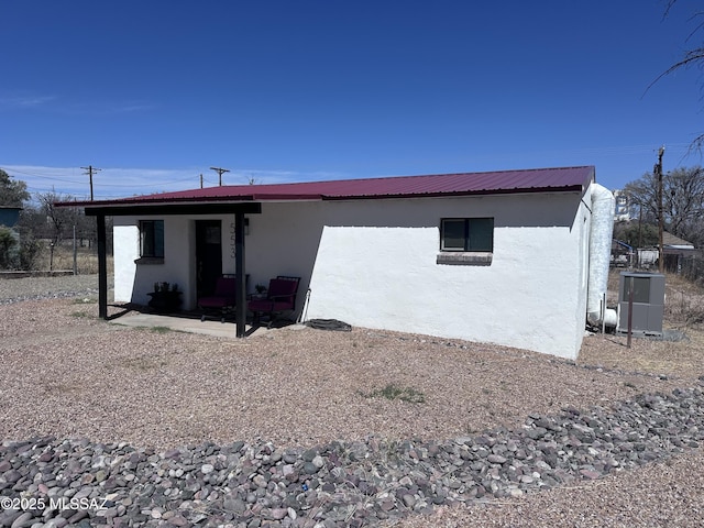 back of property with stucco siding, metal roof, and a patio