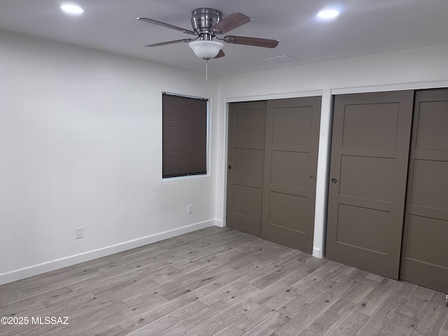 unfurnished bedroom with recessed lighting, two closets, light wood-type flooring, and baseboards