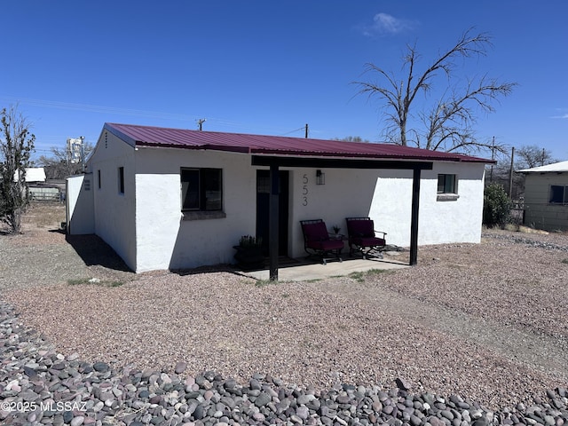 rear view of property featuring metal roof, a patio area, and stucco siding