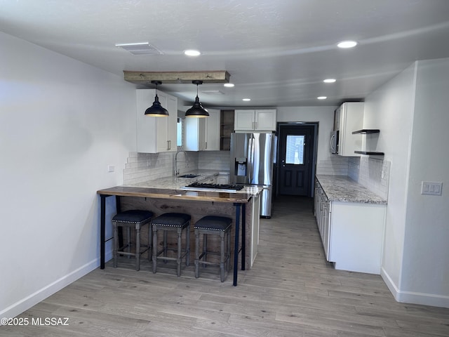 kitchen featuring visible vents, a peninsula, a sink, stainless steel appliances, and a kitchen breakfast bar