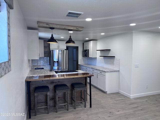 kitchen featuring light wood-type flooring, visible vents, a peninsula, appliances with stainless steel finishes, and a breakfast bar area