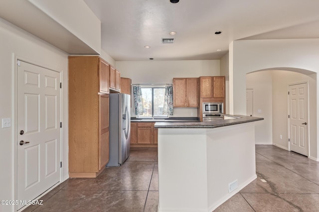 kitchen with stainless steel appliances, arched walkways, dark countertops, and visible vents