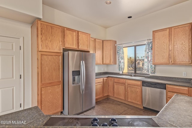 kitchen with dark countertops, appliances with stainless steel finishes, dark tile patterned flooring, and a sink