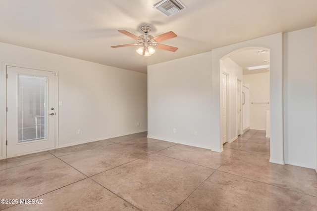 empty room featuring arched walkways, visible vents, concrete floors, and ceiling fan