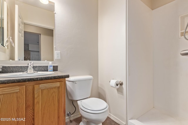 full bath featuring baseboards, toilet, vanity, and walk in shower