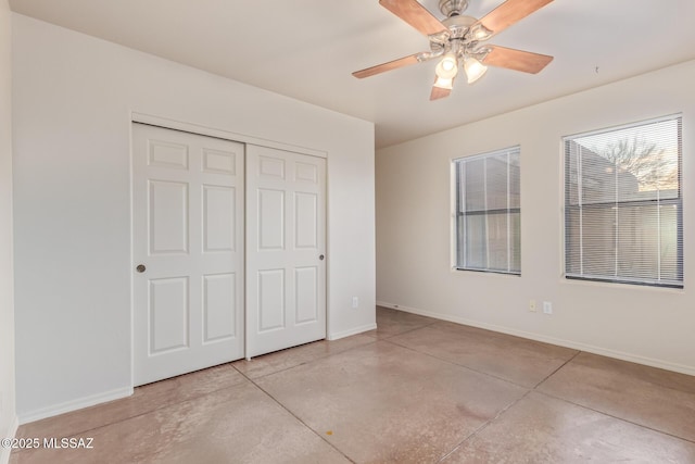 unfurnished bedroom featuring a closet, a ceiling fan, concrete floors, and baseboards