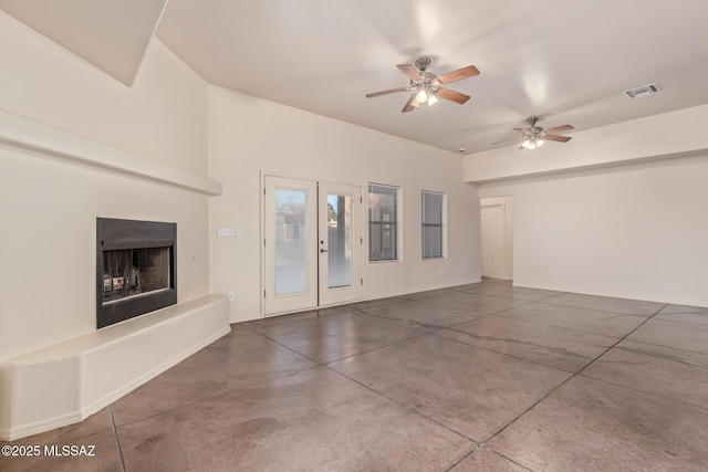 unfurnished living room with a ceiling fan, finished concrete flooring, a fireplace with raised hearth, and visible vents