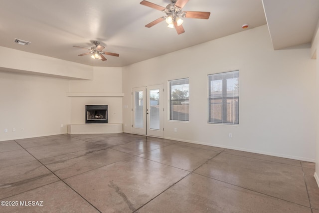 unfurnished living room with visible vents, a fireplace with raised hearth, concrete floors, baseboards, and ceiling fan