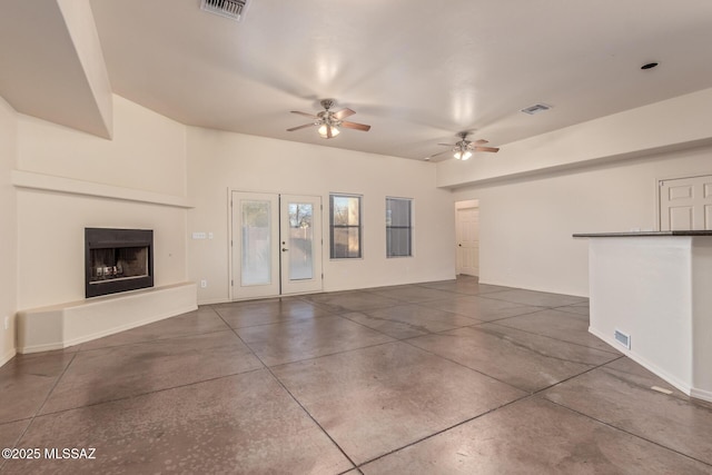 unfurnished living room featuring visible vents, a fireplace with raised hearth, a ceiling fan, and finished concrete floors