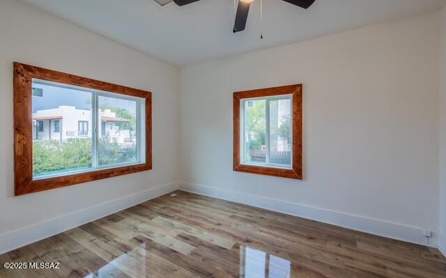 spare room featuring baseboards, wood finished floors, and a ceiling fan