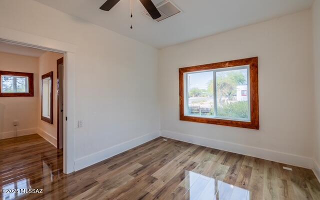 unfurnished room featuring a wealth of natural light, baseboards, and wood finished floors