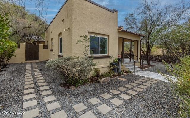 view of property exterior with stucco siding and a gate