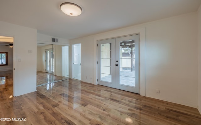 empty room featuring french doors, visible vents, and wood finished floors