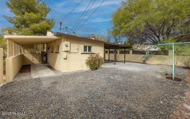 view of home's exterior with an attached carport and fence