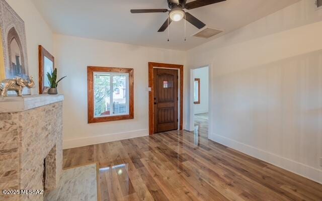 foyer featuring a fireplace with flush hearth, visible vents, baseboards, and wood finished floors