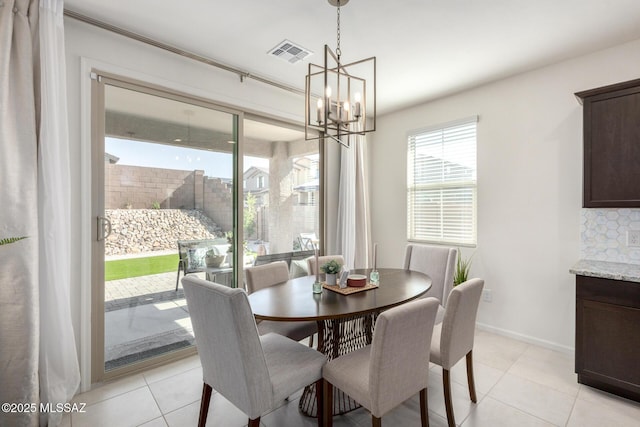 dining area featuring light tile patterned floors, visible vents, a notable chandelier, and baseboards