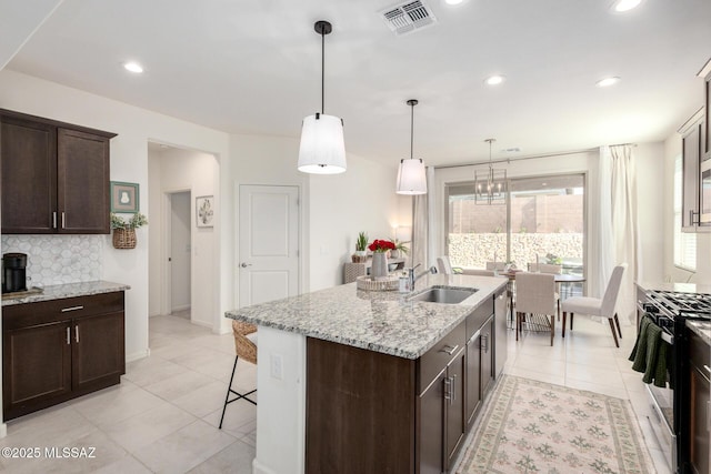 kitchen featuring visible vents, dark brown cabinets, decorative backsplash, appliances with stainless steel finishes, and a sink