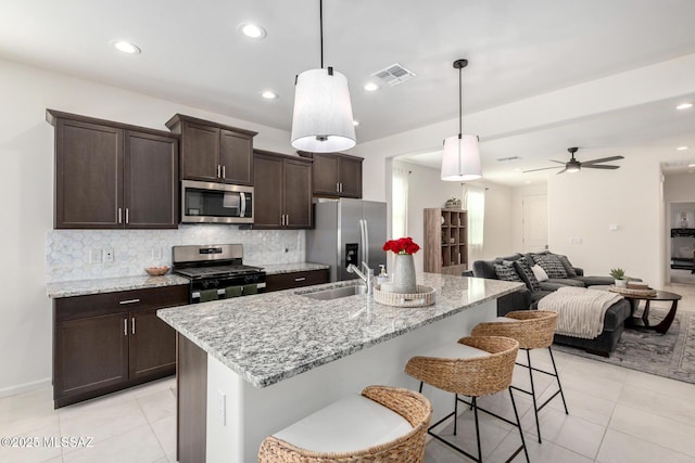 kitchen with visible vents, backsplash, dark brown cabinetry, stainless steel appliances, and a sink