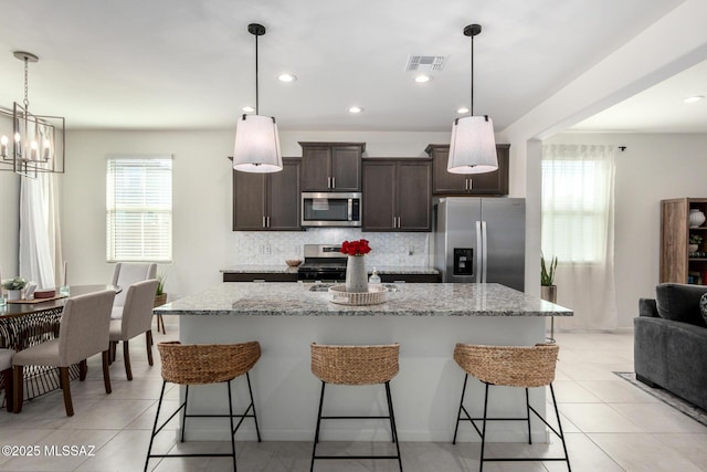 kitchen featuring stainless steel appliances, a kitchen breakfast bar, dark brown cabinetry, and tasteful backsplash